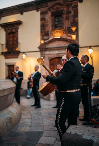 San Miguel de Allende, Mexico - January 12, 2022: Mariachis musicians wearing  traditional Mexican clothes  performing in front of the famous La Parroquia de San Miguel Arcangel Church.