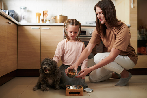 Mother showing daughter how much kibble to put in dogs bowl