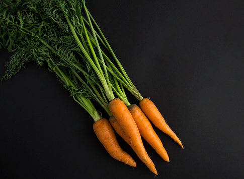 Top view of raw carrot on the black background. Close-up. Copy space.