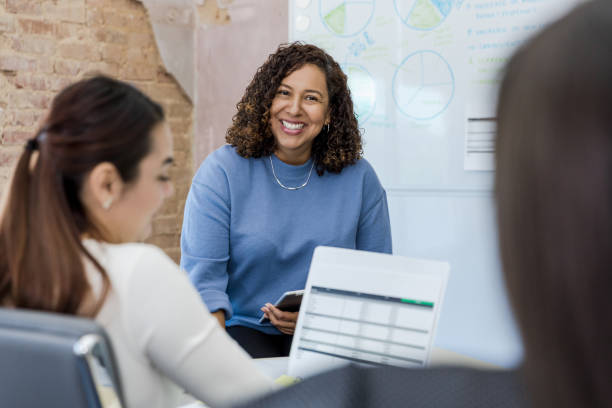 istock Female financial advisor smiles while employees review spreadsheets 1408262095