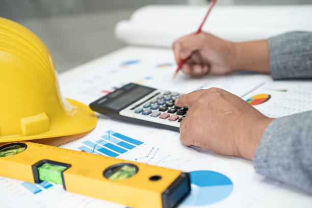 istock Asian engineer with plan project blueprint, graph and yellow helmet and engineering construction tools. 1408263391