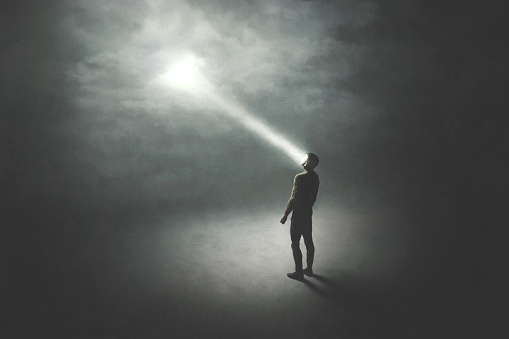 illustration of man illuminated by a beam of light from the sky, surreal abstract concept
