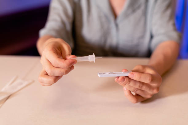 istock Woman applying test sample to a COVID-19 self testing kit at home 1408265156