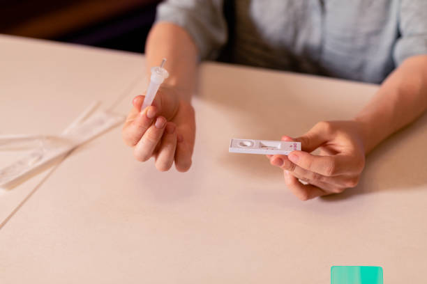 istock Woman applying test sample to a COVID-19 self testing kit at home 1408265311