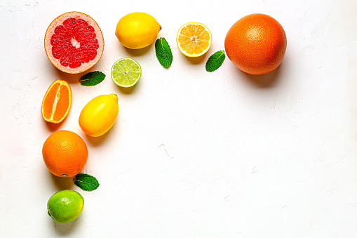 Fresh lemon, orange, grapefruit, lime, green leaves on light background, top view. Citrus Juice Concept, Vitamin C, Fruits.