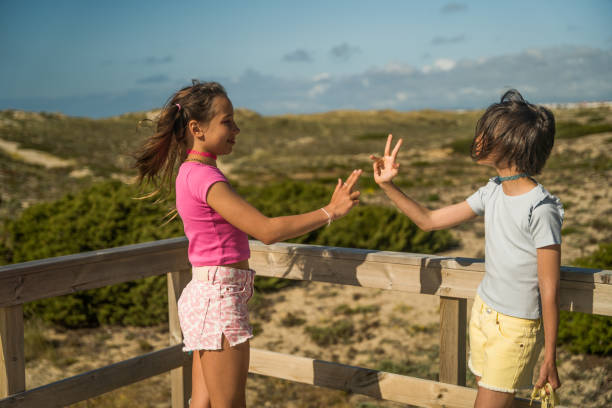 istock Two girls gesturing and playing at their own game while walking together 1408267109