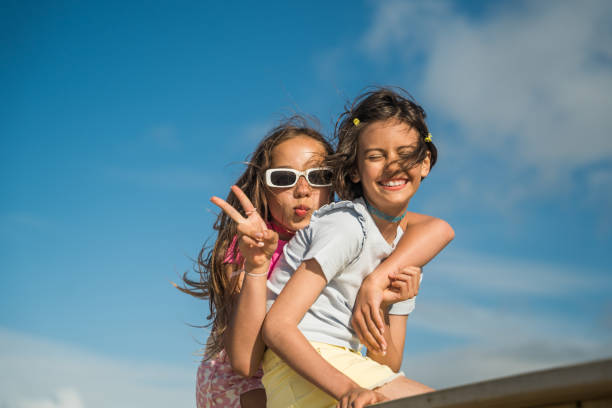 istock Smiling kid girls gesturing and embracing while having fun on the bridge 1408267183