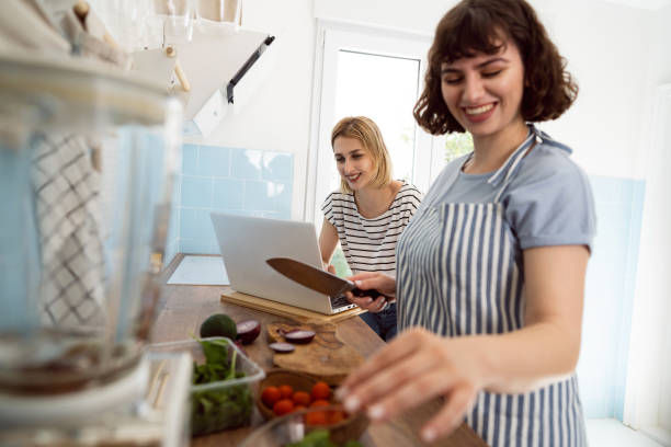 istock Woman working on laptop while her girlfriend makes the salad 1408270038