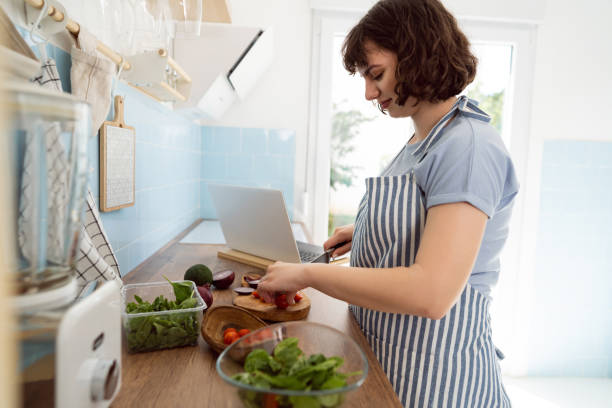 istock Young Caucasian woman making salad in the kitchen 1408270073