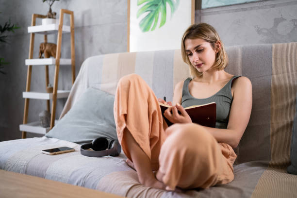 istock Caucasian woman journaling while sitting on the sofa 1408270095
