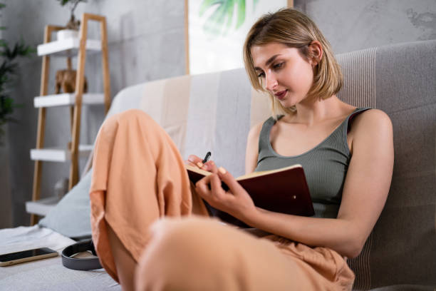istock Caucasian woman journaling while sitting on the sofa 1408270130