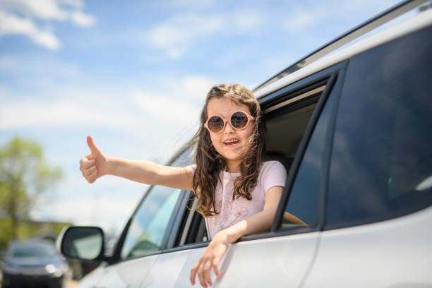 Young girl looking out of car window smiling stock photo