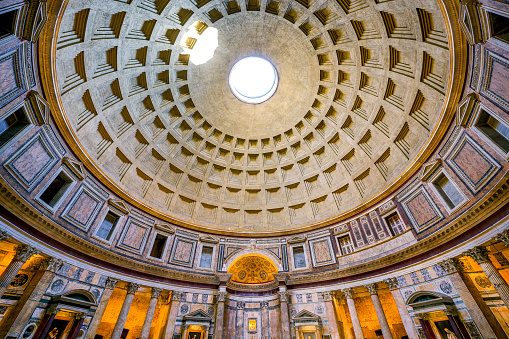 An impressive wide view inside the majestic Roman Pantheon, in the heart of Ancient Rome, with the central apse. Built in 27 BC by the Consul Marco Vispanio Agrippa for the Emperor Augustus and dedicated to all the Roman divinities, the majestic Pantheon is one of the best preserved Roman structures in the Eternal City and in the world. In addition, the Pantheon is also a Catholic church consecrated in 609 AD by Pope Bonficio IV and called the Basilica of Santa Maria ad Martyres. Within its perimeter some members of the Italian royal family and famous artists are buried, including the painter Raphael, a great protagonist of Renaissance art. The dome of the Pantheon, built in concrete and brick, is a masterpiece of engineering and the prototype of all the domes subsequently built in Christian churches in Europe. With a diameter of 43.44 meters, it is still the largest dome in the world today. In 1980 the historic center of Rome was declared a World Heritage Site by Unesco. Super wide angle image in High Definition format.