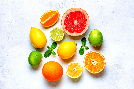 Front view of various kinds of whole and sliced citrus fruits like grapefruit, orange, tangerine, lime and lemon isolated at the center of the image on white background.