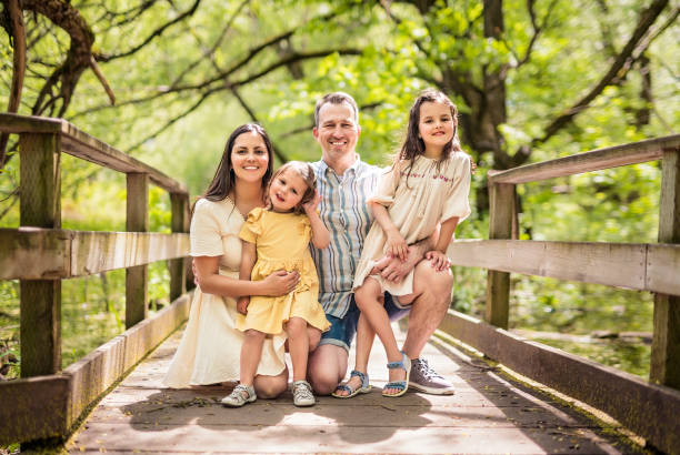 Father and mother with the daughters having fun outside in forest