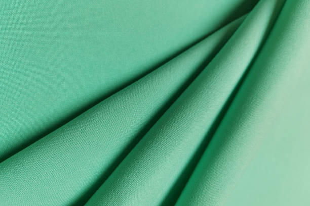 istock Green crumpled or wavy fabric texture background. Abstract linen cloth soft waves. Gabardine wool fabric. Merino yarn. Smooth elegant luxury cloth texture. Concept for banner or advertisement 1408275415