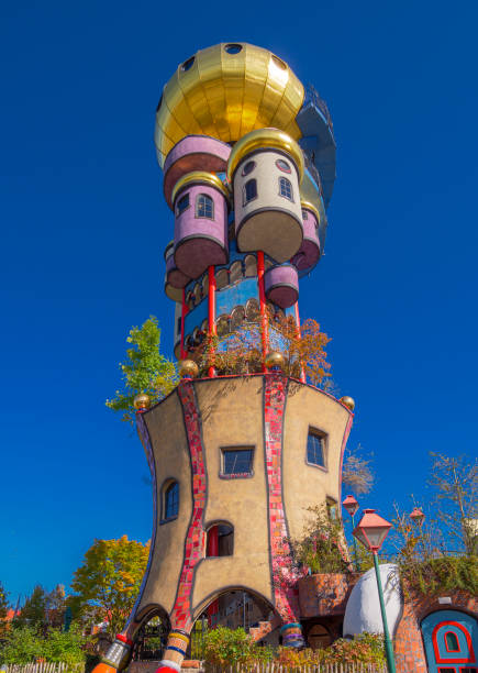 A scenic view of a historic brick water tower amid leafy green foliage and blooming trees under a clear blue sky, perfectly embodying springtime serenity and architectural beauty in an urban setting. Prenzlauer Berg, Berlin