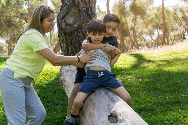 instructrice latine aidant l’enfant à glisser sur un tronc d’arbre - teaching field trip classroom child photos et images de collection