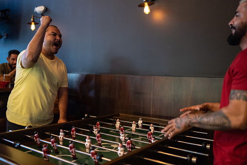 Friends playing foosball at a bar