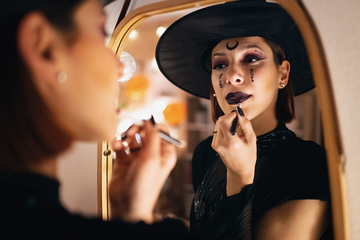 Young Caucasian woman doing make-up for Halloween party.
