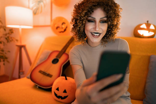 istock Beautiful young woman using phone while preparing for the Halloween party 1408280248