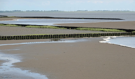 The Wadden Sea at the Leybucht between tides. It's changing from low tide to high tide. The row of poles with bushwood in between are fascines. Probably to prevent the sea taking the sand away.