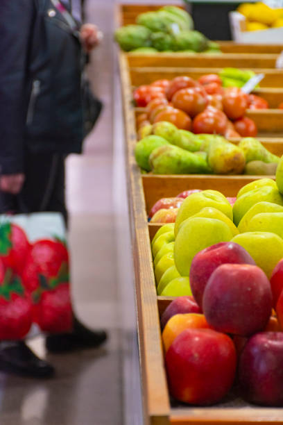 Fruit stall in a local market with a woman with a shopping bag out of focus in the background