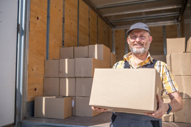 a cheerful worker unloads cartons of goods - postal worker truck driver delivering delivery person imagens e fotografias de stock