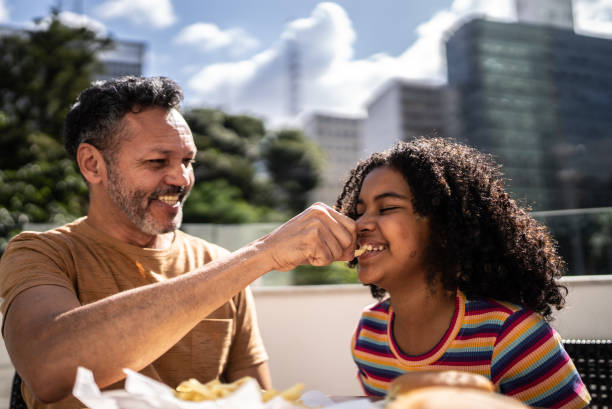 father giving french fries to daughter - couple restaurant day south america imagens e fotografias de stock