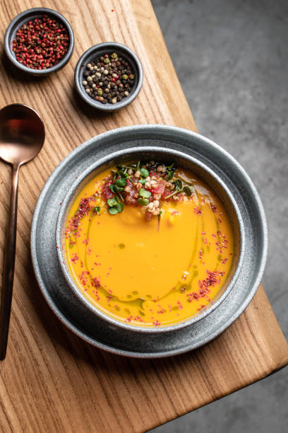 um prato de sopa de creme de abóbora guarnecido com microverdes e tomates em uma mesa de madeira, vista para cima. comida restaurante - cilantro seed coriander seed spice - fotografias e filmes do acervo