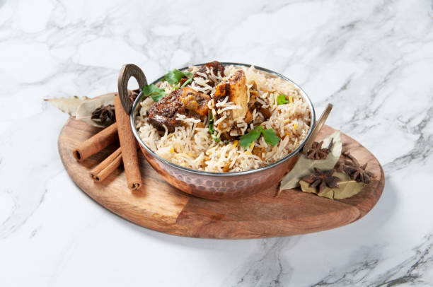 Lamb Shank Biryani with raita served in a dish isolated on wooden board side view on dark background stock photo