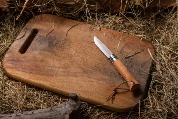 Photo of Folding French knife with wooden handle. Knife on a cutting board. Copy space.