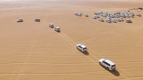 4x4 SUVs cars driving through the sand dunes in the desert of Abu Dhabi. Stock. Top view on SUVs in the desert.