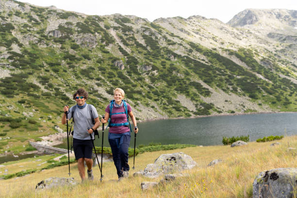istock Two hikers with a backdrop of mountains and a lake 1408293121
