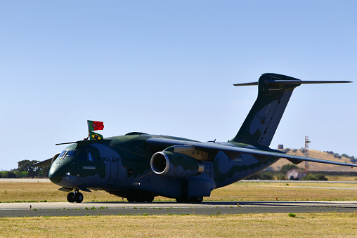 Beja, Portugal: Embraer C-390 / KC-390 Millennium on the runway - medium-size, twin-engine, jet-powered military transport aircraft produced by the Brazilian aerospace manufacturer Embraer - Brazilian and Portuguese flags - Air Base No. 11 - Base Aérea Nº 11, BA11.
