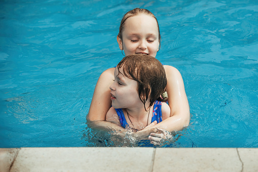 children, two girls sisters have fun and actively spend time in the water of the pool on hot days of summer