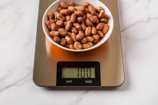 istock Raw dried peanut in a bowl on a digital kitchen scales. Weigh 100 g whole peeled monkey nut for ready to eat dietary nutrition. Healthy vegetarian snack of organic groundnut seeds. 1408296548