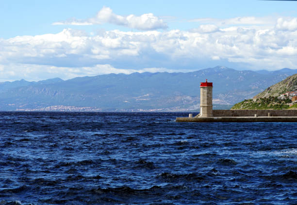 istock The choppy, wavy blue sea and the lighthouse on the waterfront 1408296580