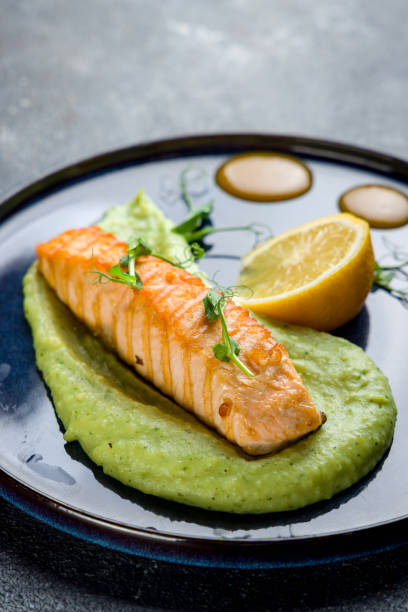istock Salmon steak on the grill with mashed potatoes with spinach with lemon on blue plate on grey table macro close up vertical 1408296795