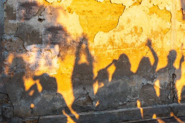 istock Shadows of dancing people on an old stone wall at sunset time. 1408300128
