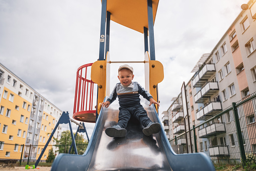 Child slide. Boy playing on outdoor playground. Kids play on school or kindergarten yard. Healthy summer activity for children.
