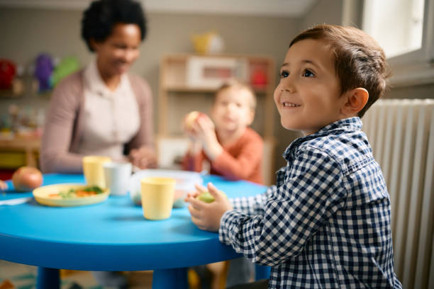 istock Happy small boy enjoying in lunch at kindergarten. 1408303895