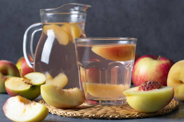 Compote of peaches and apples in a glass and jug on a dark gray background Compote of peaches and apples in a glass and jug on dark gray background apple compote stock pictures, royalty-free photos & images