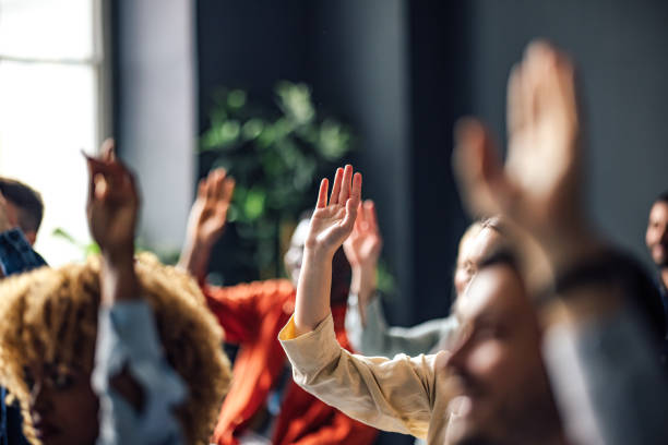 group of anonymous people raising hands on a seminar - education stockfoto's en -beelden