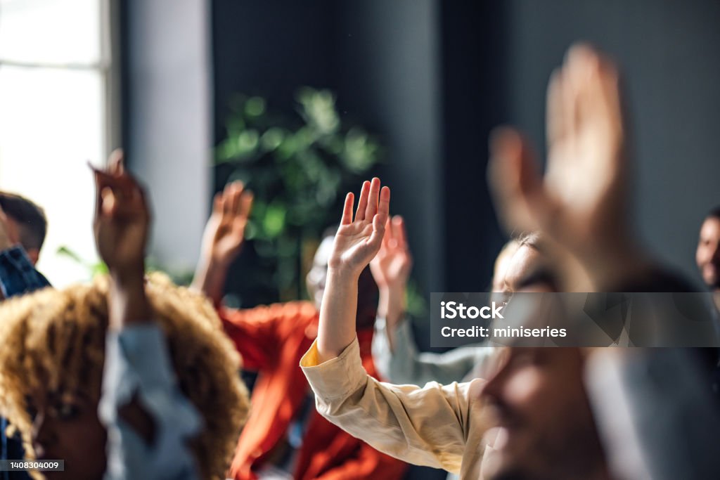 Group of Anonymous People Raising Hands on a Seminar Group of people sitting on a seminar. They have their hand raised. Question Mark Stock Photo