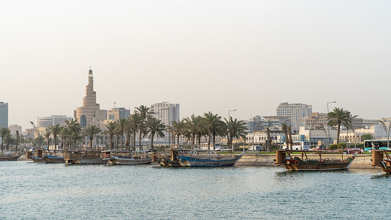 Multiple wooden traditional fishing dhows docked in the doha corniche.