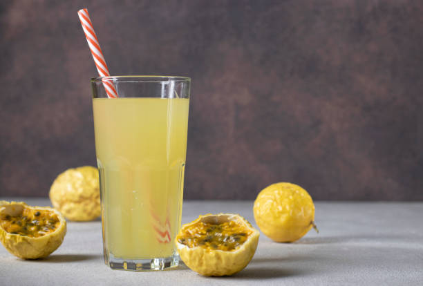 istock Lemonade or cocktail from passion fruit in tall glass with drinking straw on brown background 1408306342