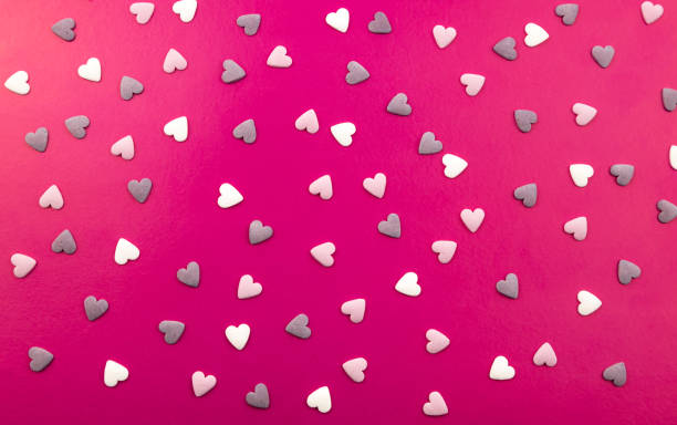 Romantic composition with hearts on a pink background. Valentine's Day. Many small colorful hearts. Background texture