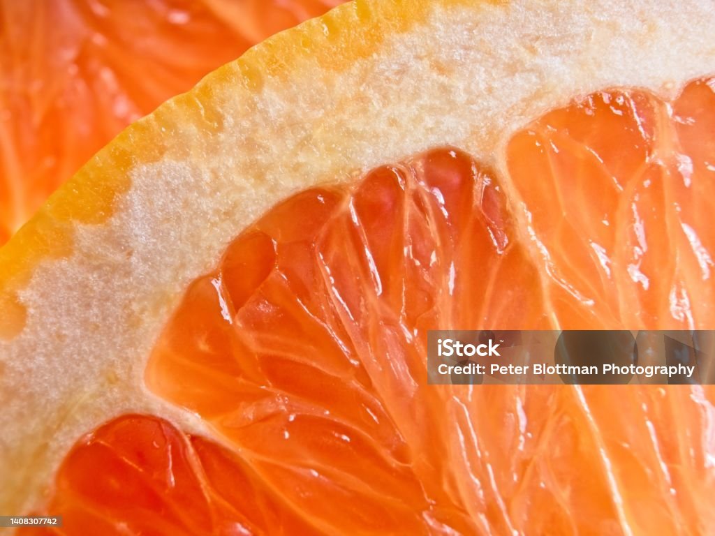 A wholesome slice of ruby red grapefruit, a vegan food packed with vitamin C A wholesome slice of ruby red grapefruit, a vegan food packed with vitamin C. Macro of grapefruit showing the texture and details of this citrus fruits segments. Macrophotography Stock Photo