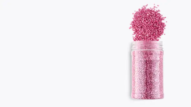 A pack of pink glitter crystal salt for aroma spa. Shimmering sea salt isolated on white background. Can of pink bath salt. The idea of home relaxation, aromatherapy and self care. Copy space.